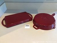 Two pieces of dark red Hell's Kitchen enamel cast iron cookware shown from top, including rectangular grill pan and round skillet.