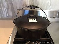 Front view of the Lodge cast iron Dutch oven with lid on, showing the wire ball handle and black seasoned cast iron surface.