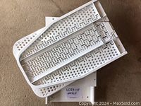 Top view of the folded white metal ironing board with perforated pattern, showing its compact and foldable design.