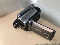 Panasonic SDR-H40P camcorder, silver and black finish, showing the front with lens and HDD label, placed on a white surface.