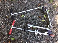 Two Razor scooters placed on gravel surface, one with kick stand, showing overall condition and build