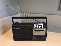 Front view of the Sony portable radio with extended telescoping antenna and carrying handle, showing the speaker grill and front panel details.
