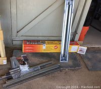 New, unassembled Stablemate tool stand parts including steel rails, metal brackets, hardware and packaging box.