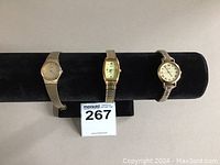 Three Seiko ladies' watches on a black display with gold and silver tone bands