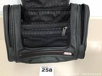 Front view showing zippered mesh organizational pocket and TUMI logo plaque