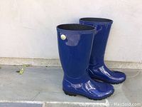 Pair of blue UGG Shayne tall rubber rain boots standing upright side by side showing outer side.