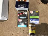 Overview image showing multiple boxes and packages of nails and fasteners on a floor surface, including clearly visible brands and labels.
