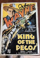 Metal sign featuring a John Wayne movie poster style illustration with bold orange and white text.
