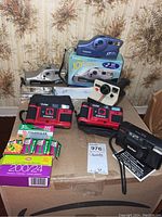 Lot overview showing two Vivitar Champion 35 cameras, two Vivitar PS-35 cameras, two Joycam cameras (one boxed), Polaroid Land camera and assorted 35mm film rolls on cardboard box