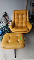 Front view of mustard yellow chair and ottoman in garage, showing tufted upholstery and metal star base