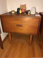 Front view of teak nightstand with decorative objects on top