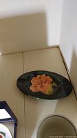 Moorcroft ashtray with orange flower on dark background