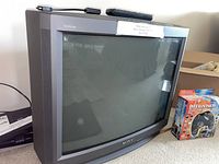Front and angular view of Sony Trinitron 27 inch CRT color TV with curved screen and grey casing showing the entire CRT unit.