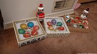 Three boxes on carpet showing assorted vintage Christmas ornaments and two ceramic snowman figurines