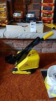 Yellow Tonka shovel toy vehicle shown with black shovel, yellow handle, and black tracks on a carpet and stone hearth background.