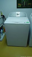 Front view of white Whirlpool Cabrio HE top-loading washing machine showing lid and control panel.