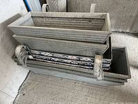 Photo of eight galvanized metal hanging planter boxes stacked together, showing their ribbed texture and hanging brackets.