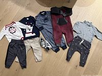 Full display of assorted baby clothes and Adidas sneakers on wooden floor.