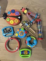 Photo showing nine colorful baby musical toys including xylophone, maracas, tambourines, hand drum, and shaker
