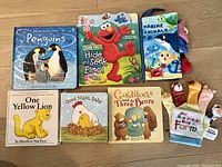 Seven children's board books featuring animals, characters like Elmo, and nursery rhymes with bright colorful covers. Books include fabric and finger puppet elements in some.