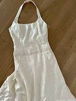 Front view of white silk wedding gown laid flat, showing halter neckline and beaded waist.