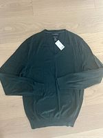 Forested green V-neck men's sweater laid flat to show full front view, new with tags still attached