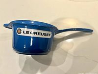 Side view of Lapis blue Le Creuset saucepan with handle and visible brand sticker.