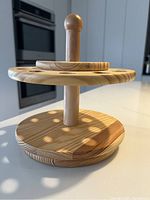 Side view of the solid wood spinning rack showing the two circular tiers and the wooden spindle with round top knob.