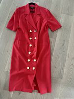 Full view of vintage Louis Féraud red dress laid flat showing double-breasted front button design, short sleeves, lapel collar, and pockets.