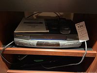 Panasonic PV-8456 VCR unit displayed with remote and user manual placed on top, showing front details with various input jacks and control buttons.