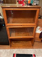 Front view of the wooden 3-tier barrister bookcase showing two closed glass doors and the bottom open compartment.
