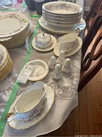 Wide view showing several stacked serving bowls, plates, gravy boats with underplates, salt and pepper shakers, butter dish with lid, all in Paragon Victoriana Rose pattern.