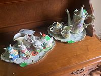 Porcelain coffee set and bunny creamer set arranged on wooden surface, showcasing overall items in the lot