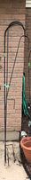 Three vertical black metal shepherd's hooks against a brick wall, tallest hook approximately 75 inches.