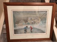 Full view of framed lithograph featuring two youth hockey players on an outdoor rink, snow-covered house in background.