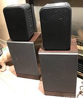 Pair of JBL62 speakers on top of pair of Pyramid 3000 5080 speakers, showing front and side views with wood grain sides on Pyramid speakers.
