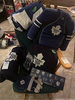 Image showing multiple Toronto Maple Leafs fan items including hockey jersey, cushion, bag, and gloves on a green chair