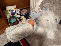 Photo of the full lot showing Fisher-Price-style toy, plastic horse, various plush toys including beaver doctor and dogs, baby doll in floral sleeping bag.