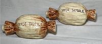 Two ceramic flasks shaped and painted like wrapped hot tamale candies, side view showing the "HOT TAMALE" label.