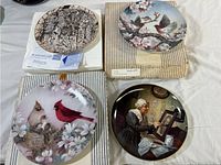Four decorative plates including two bird themed plates, one indigenous art style plate, and one artistic lady at piano plate