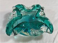 Green and clear Murano glass trinket dish with thick, wavy folded rim shown from top angle.