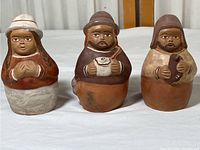 Photo showing three Peruvian terra-cotta/clay figurines side by side on a white surface