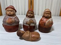 Front view of four Peruvian terra-cotta clay figurines on a wooden surface.