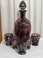 Front view of the decanter with stopper and five glasses arranged in front.