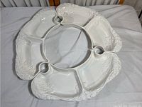 Top view of three interlocking white ceramic snack bowls with embossed leaf motifs, arranged in a circular pattern.
