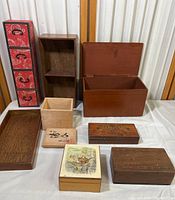 Photo showing the entire collection of eight vintage wooden boxes in various sizes and finishes arranged on a white cloth surface in front of a mirrored backdrop