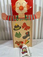 Front view of the Sevi wooden clown doll with painted accessories on the wooden base and the themed card and red ball in front.