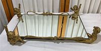 Front angled view of the rectangular mirrored tray with four cherub figurines at corners and metal ornate edges.