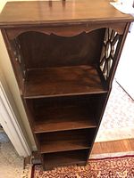 Front view of antique mahogany 4-tier shelf showing decorative side panels and four shelves