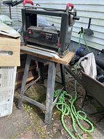 Craftsman electric planer mounted on metal stand outdoors near building.